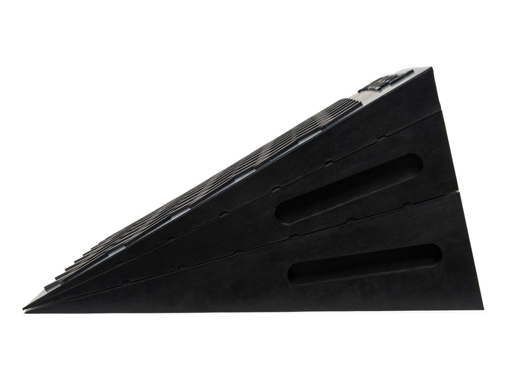 A set of black rubber vehicle ramp blocks stacked diagonally on a plain white background.