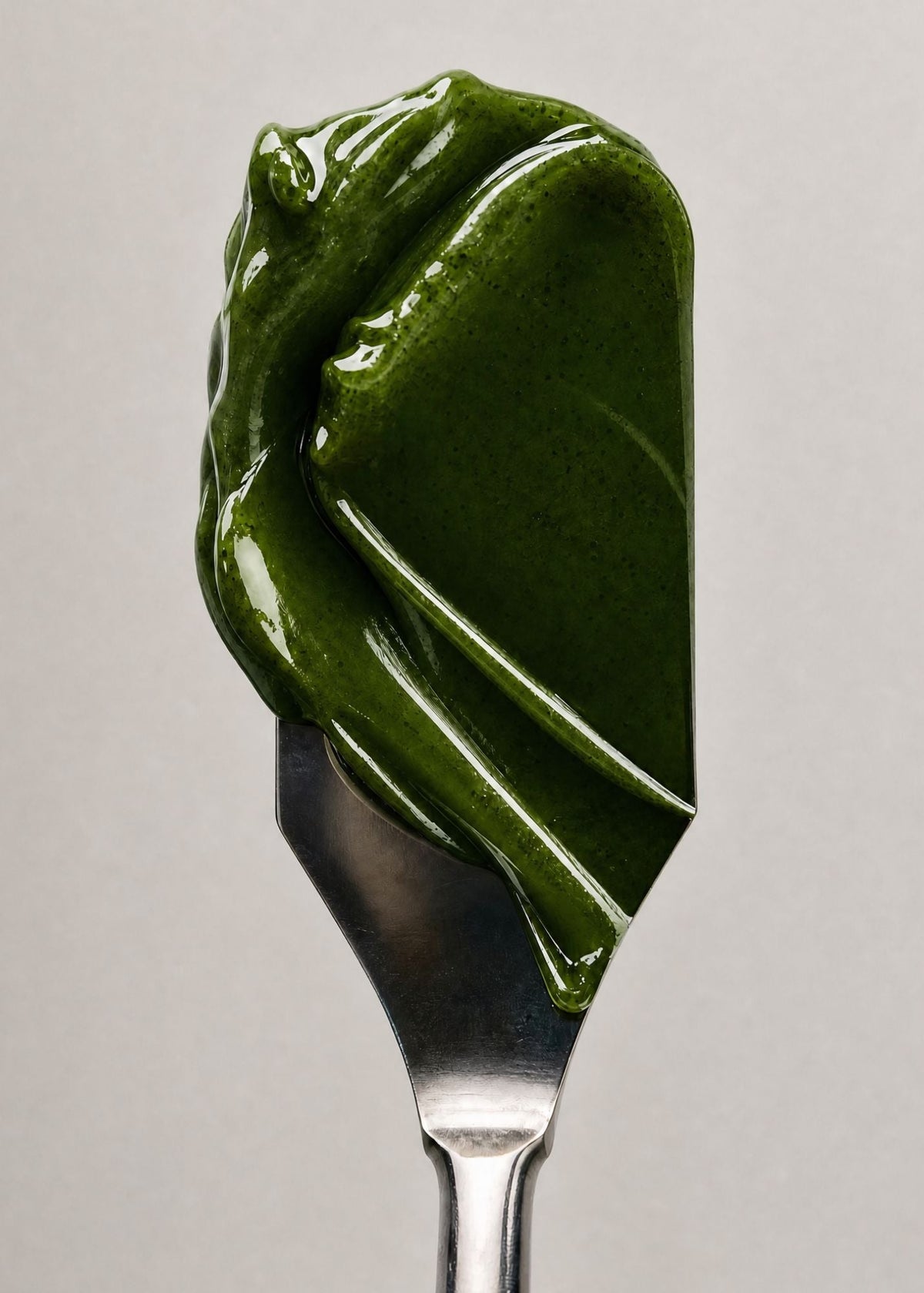 Green spreadable food on a fork against a neutral background