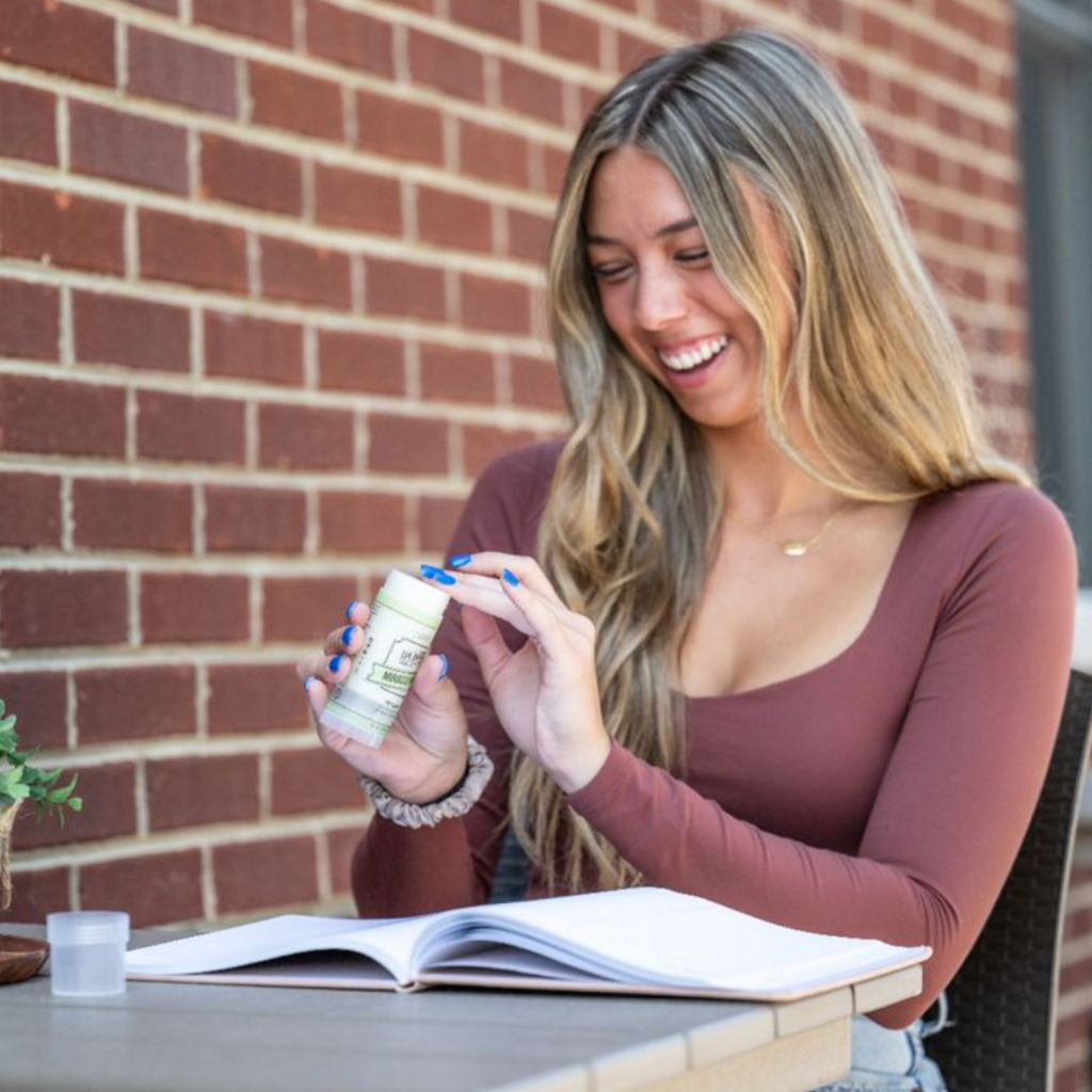 Woman holding a bottle of supplements outdoors near a brick wall