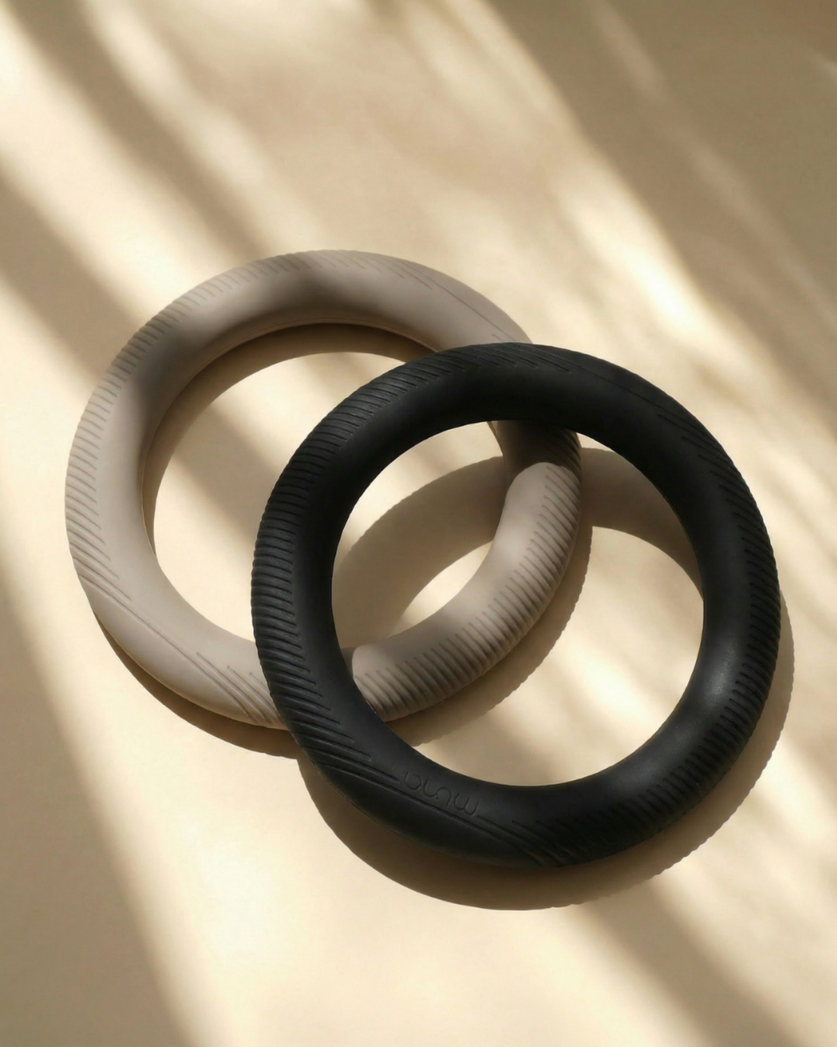 Two rings, one beige and one black, on a beige background