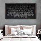 Framed quote by St. Therese above a bed with pillows and bedding.