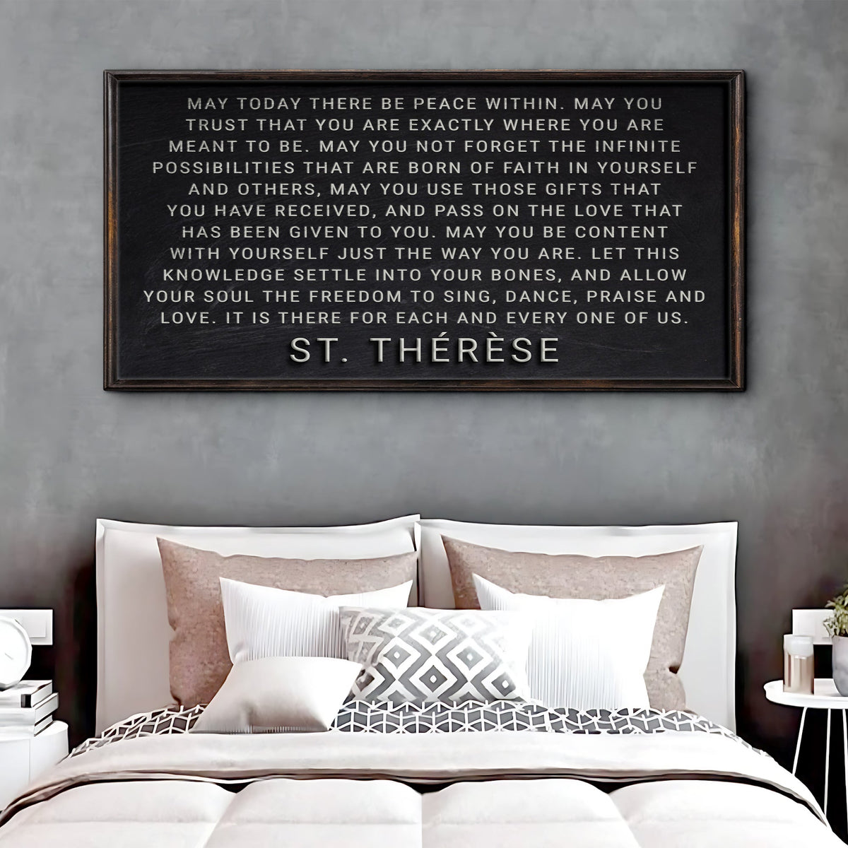 Framed quote by St. Therese above a bed with pillows and bedding.