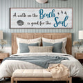 Bedroom with wooden headboard, pillows, and a large decorative sign above.