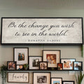 Wall with framed photos and a large Gandhi quote sign