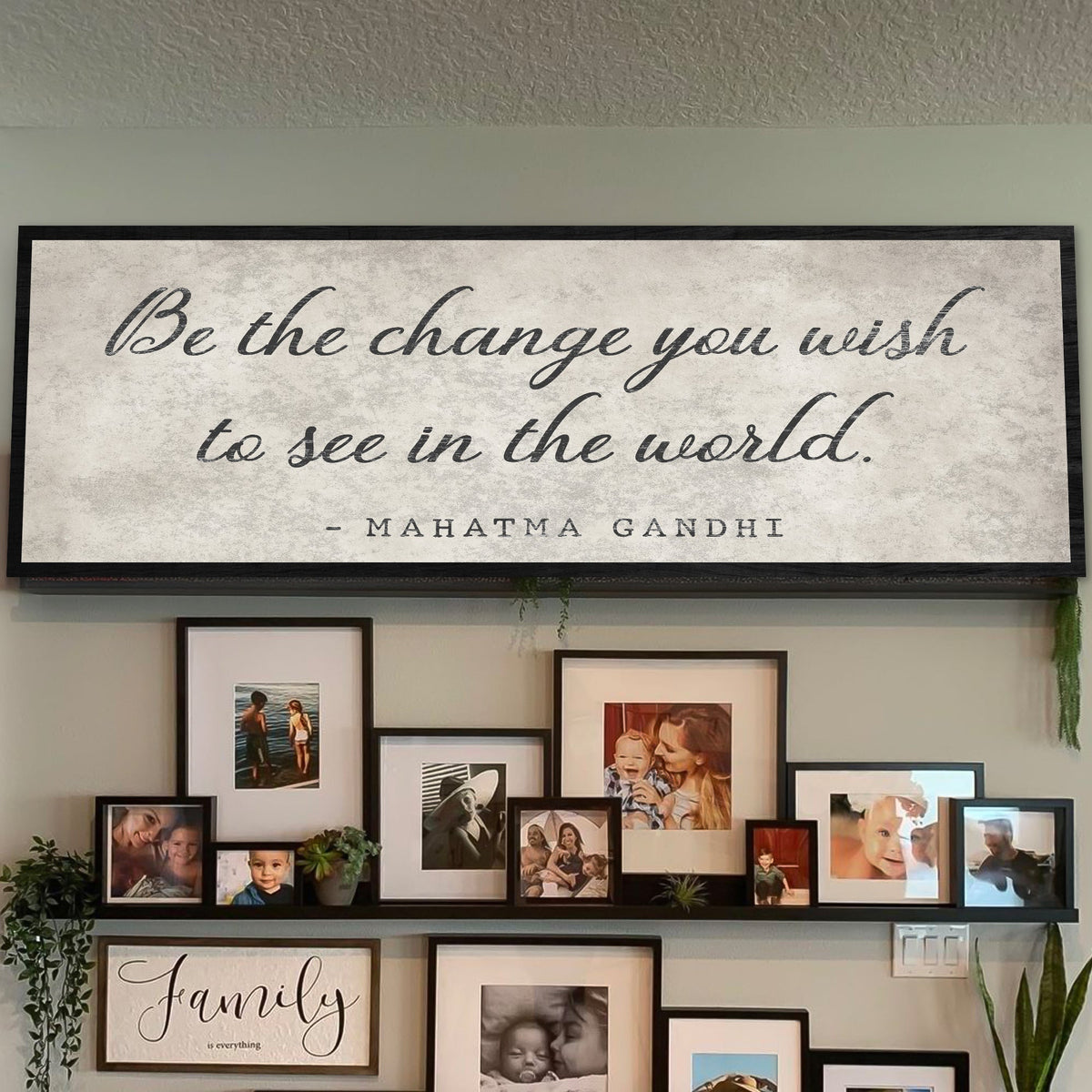 Wall with framed photos and a large Gandhi quote sign