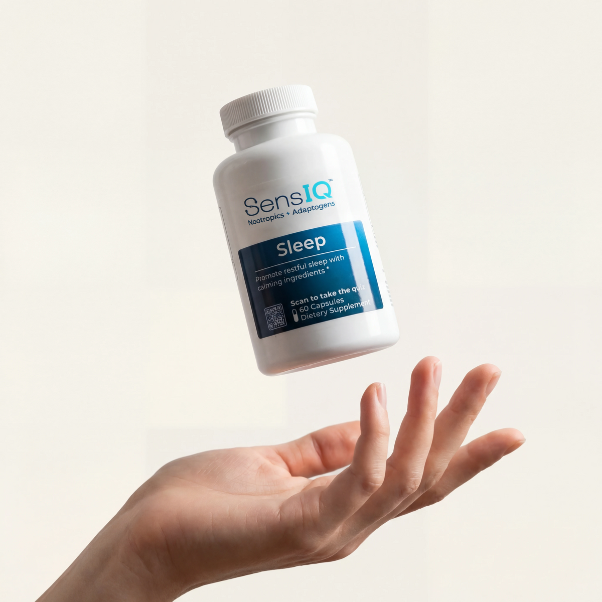 Hand holding a bottle of SensIQ Sleep supplement against a light background