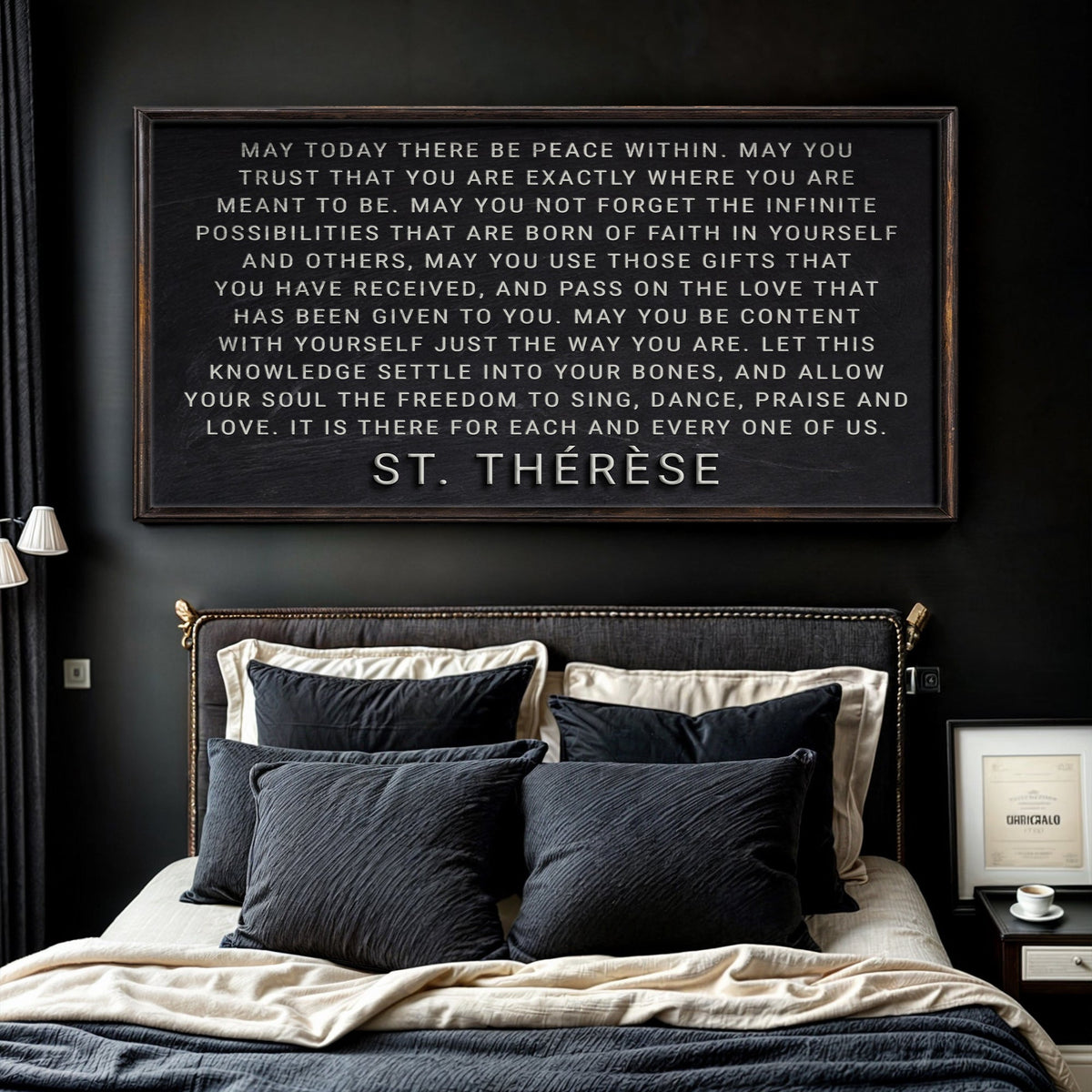 Bedroom with a quote from St. Therese on the wall above a bed with dark pillows.