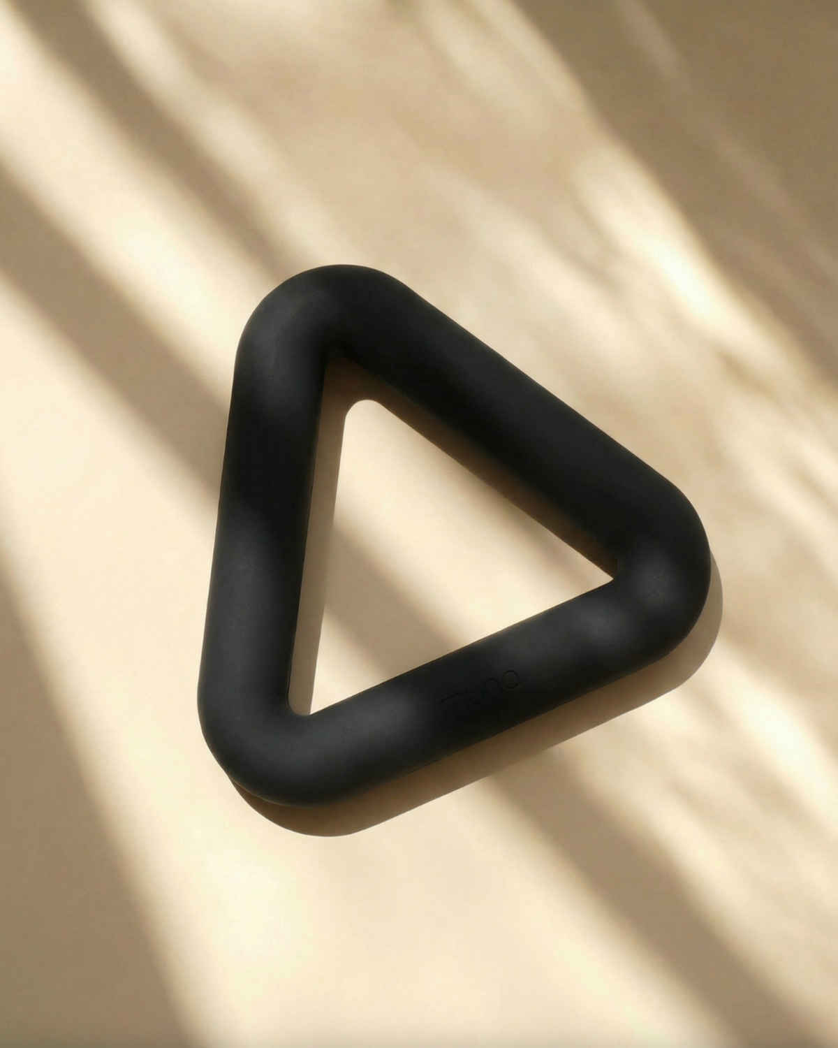 Black triangle-shaped object on a beige surface with shadows