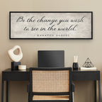 Modern office setup with a desk, chair, and framed Gandhi quote on the wall.