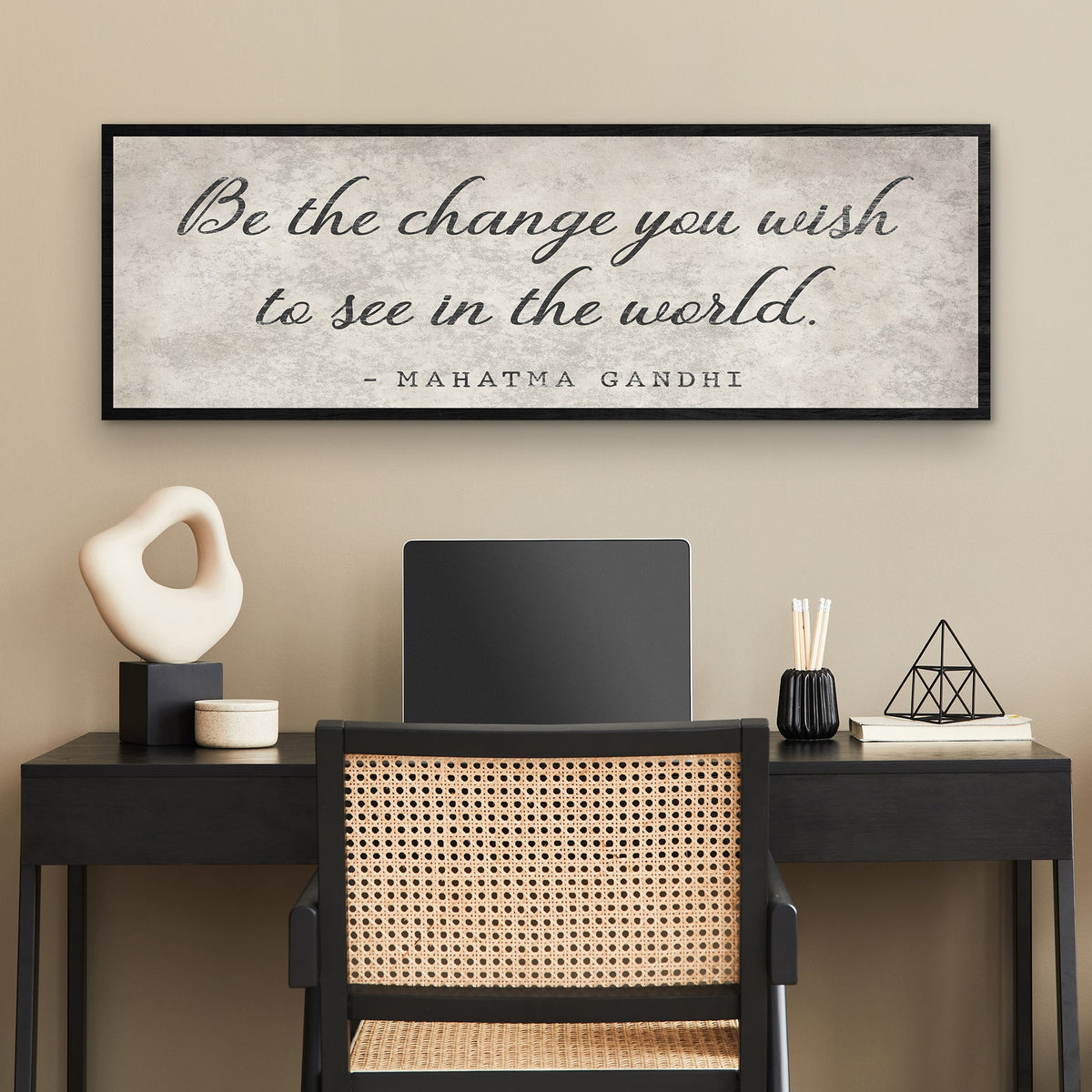 Modern office setup with a desk, chair, and framed Gandhi quote on the wall.