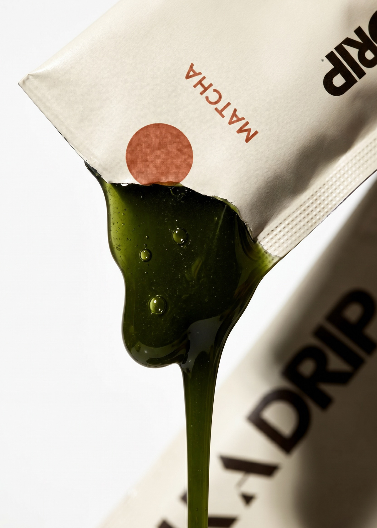 Matcha green tea package with a drop of matcha liquid on a white background