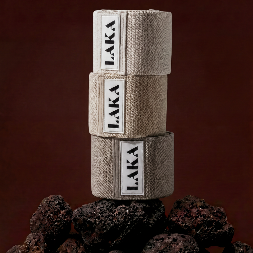 Three beige LAKA hand wraps stacked on a dark brown background with volcanic rock.
