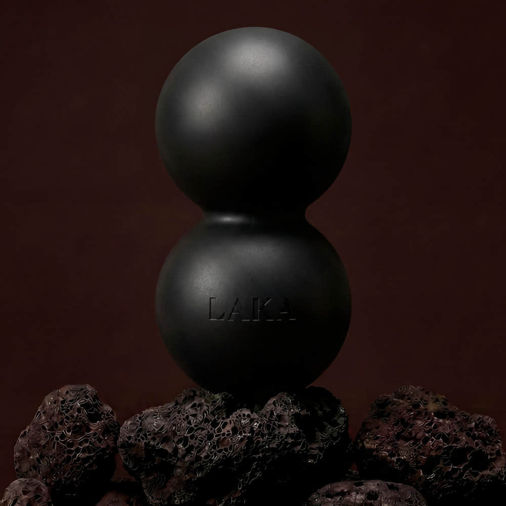 Two black spheres stacked on top of each other with a dark brown background