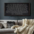 Framed St. Therese quote on a wall above a sofa with decorative pillows and a blanket.