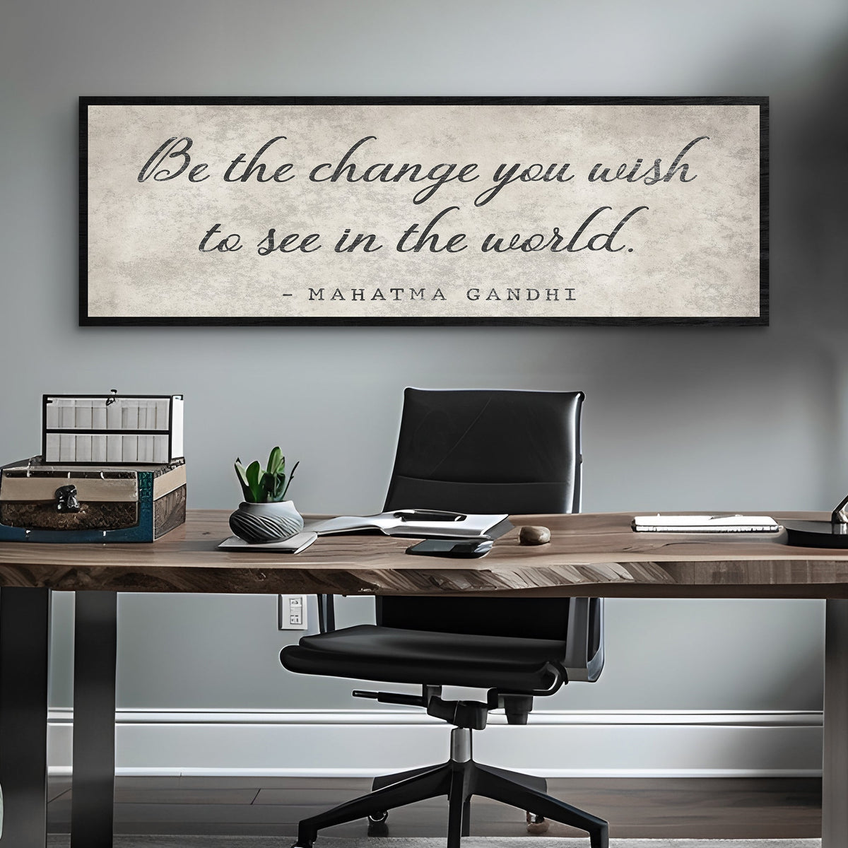 Office desk with a motivational quote by Mahatma Gandhi on the wall.