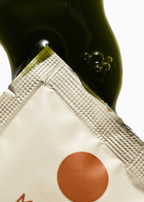 Close-up of a green bottle with a white label featuring a red circle on a white background