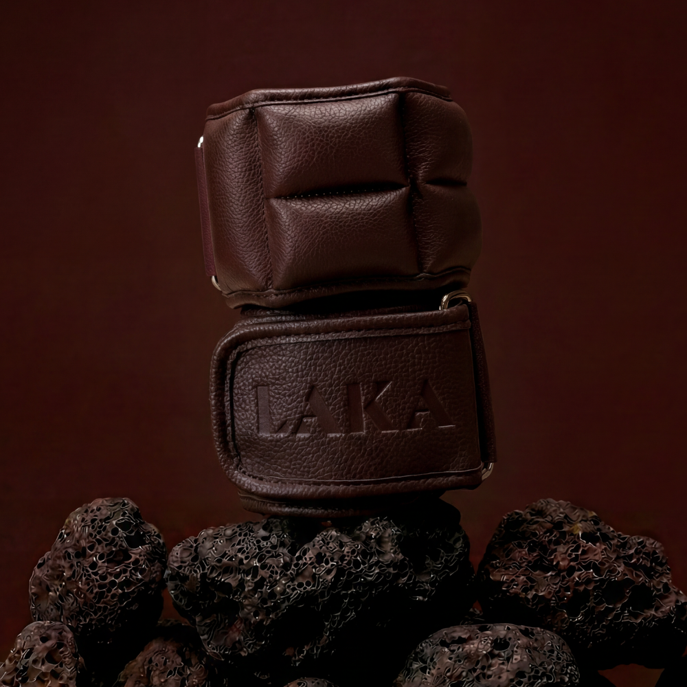 Brown leather glove with 'LAKA' branding on a dark brown background