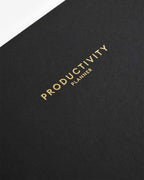 Black planner with 'Productivity Planner' text in gold on a white background