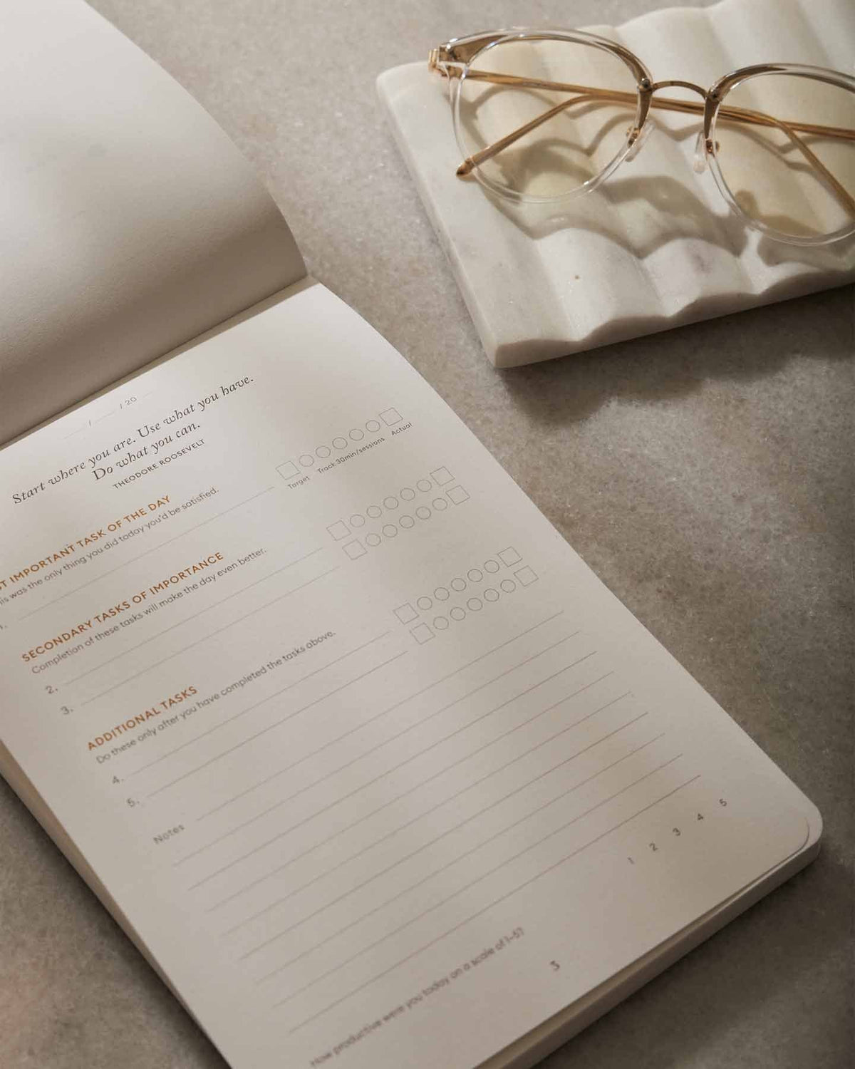 Notebook with a planner layout on a textured surface, with glasses placed on top.
