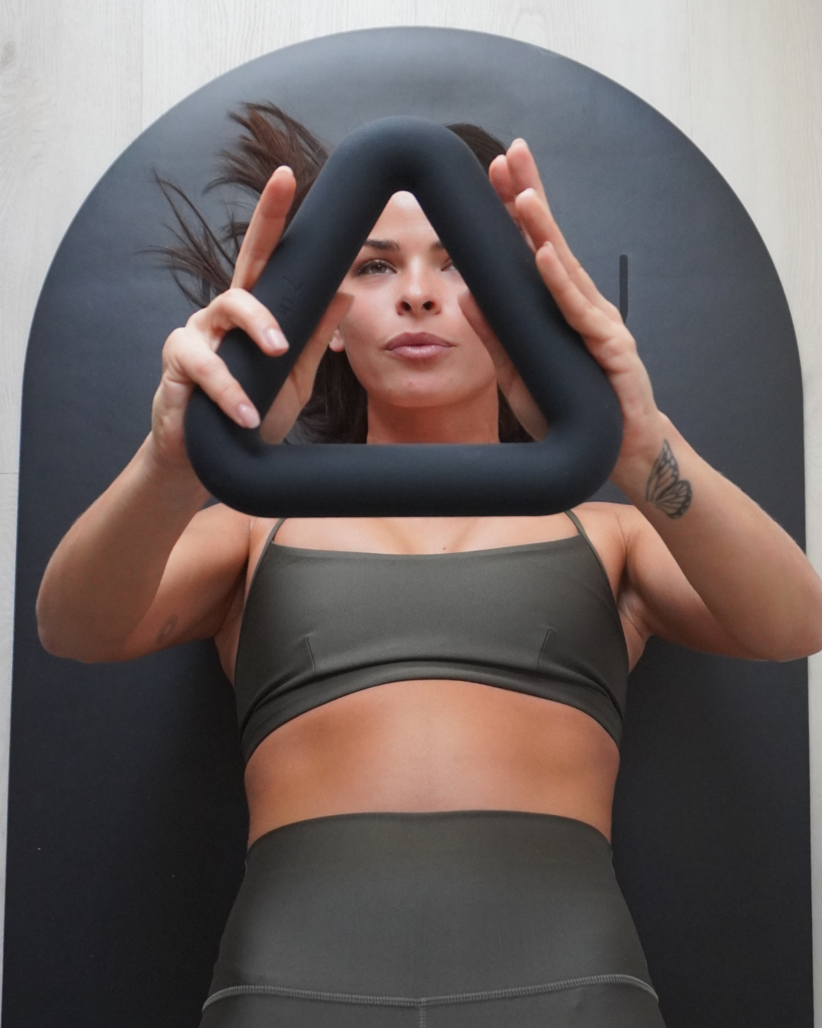 Woman holding a black ring in front of her face against a dark background