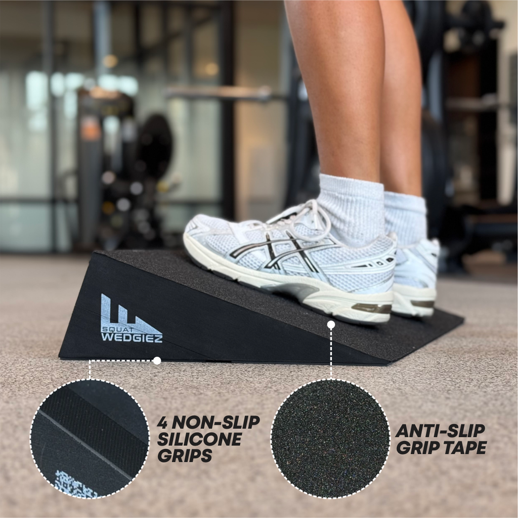 A black wedge ramp with non-slip grips and anti-slip tape, shown in a gym setting with a person stepping onto it. Two circular inset graphics highlight the textured grip surfaces.