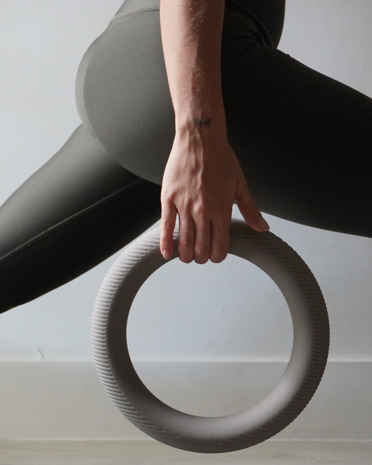 Person holding a gray gymnastic ring on a light background