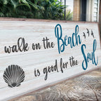 Wooden sign with 'walk on the Beach is good for the Soul' text and shell design.