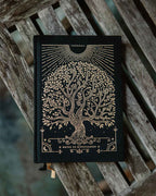 Black notebook with gold tree design on a wooden surface