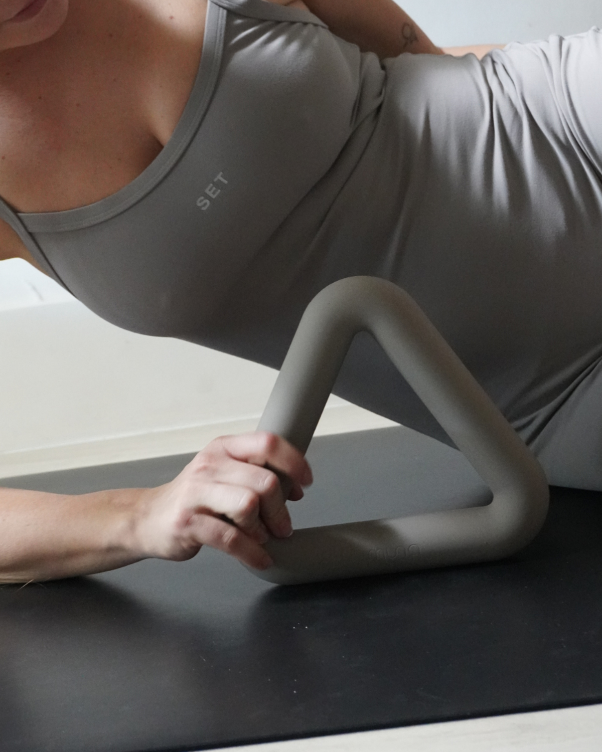 Person using a Pilates ring on a mat with a neutral background