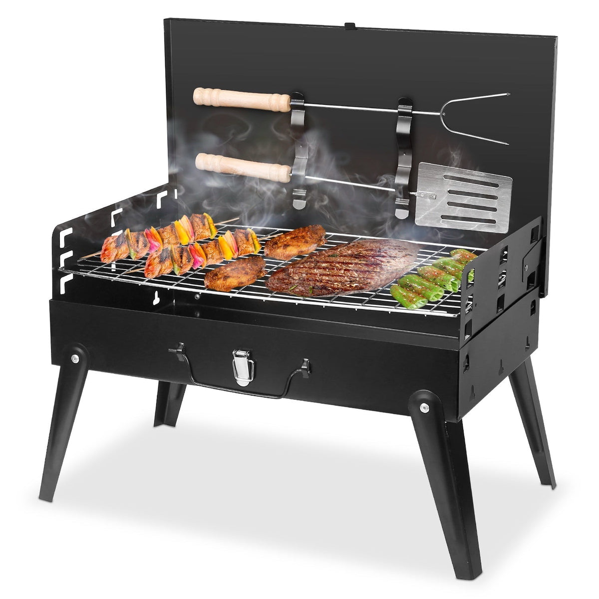 A black metal portable grill with legs, shown open and filled with food on the grate. Two hanging tools are visible on the back panel: a fork-like tool with a wooden handle and a spatula-like tool.