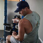 Man in a gym setting holding a supplement bottle