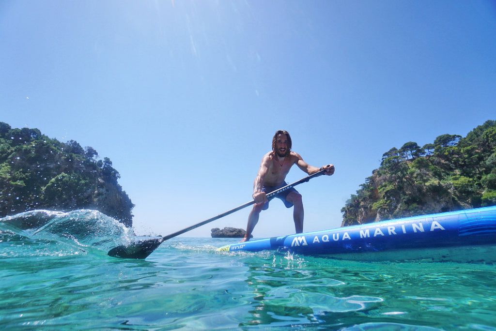 Person paddleboarding on a clear blue lake with trees in the background