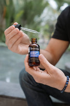 Person holding a bottle of 'Upgraded Boron' supplement with a dropper.
