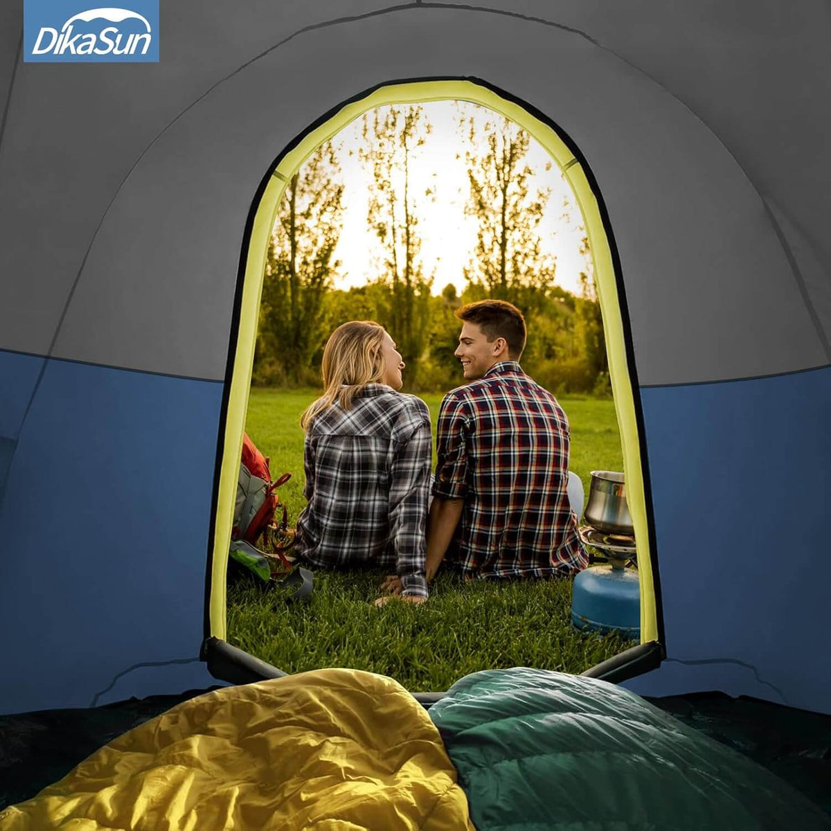 Two people sitting inside a tent with a scenic view of trees and grass outside, featuring DikaSun branding.