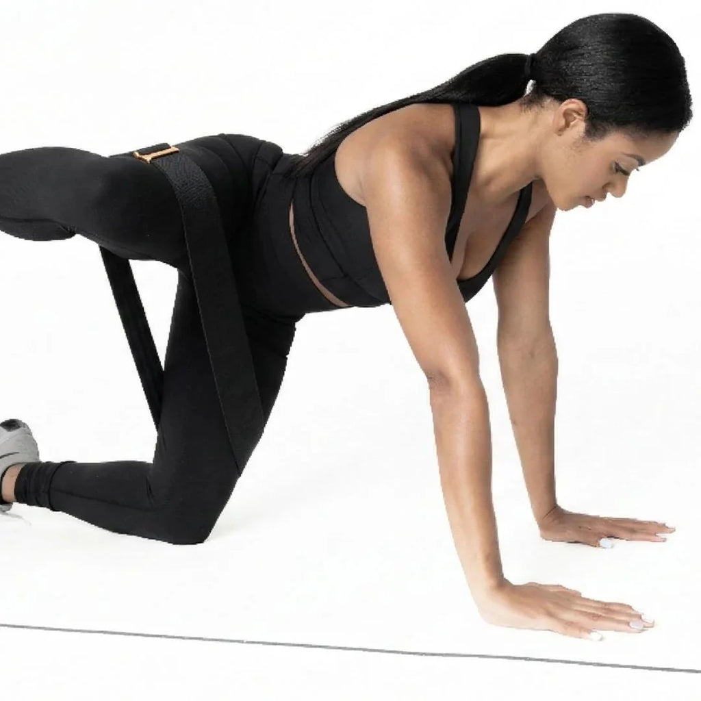 Woman in black athletic wear using a resistance band on a white background