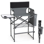Gray and black folding camp director chair with an attached side tray table, cup holder, mesh storage shelf, and side storage pocket, shown on a white background with the folded chair beside it.