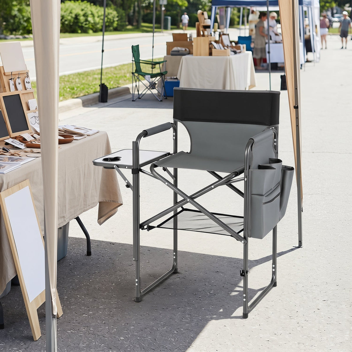 Gray director's chair with armrests on a street with outdoor furniture and tables in the background.