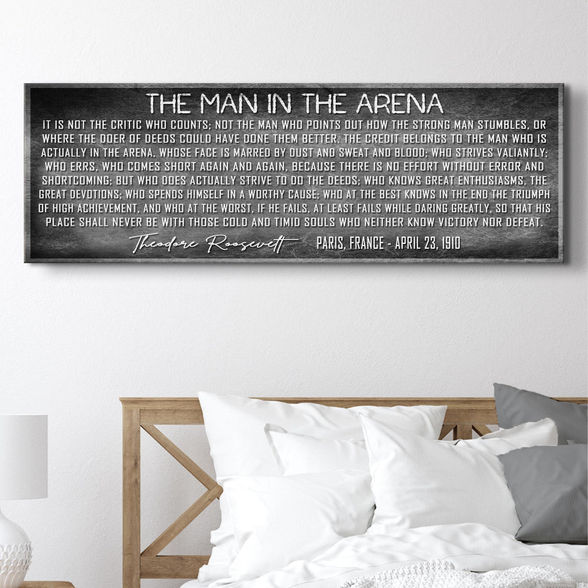 Framed quote by Theodore Roosevelt on a wall above a bed