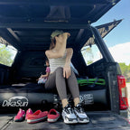 Person sitting in an open car trunk with shoes on the ground, DikaSun logo visible