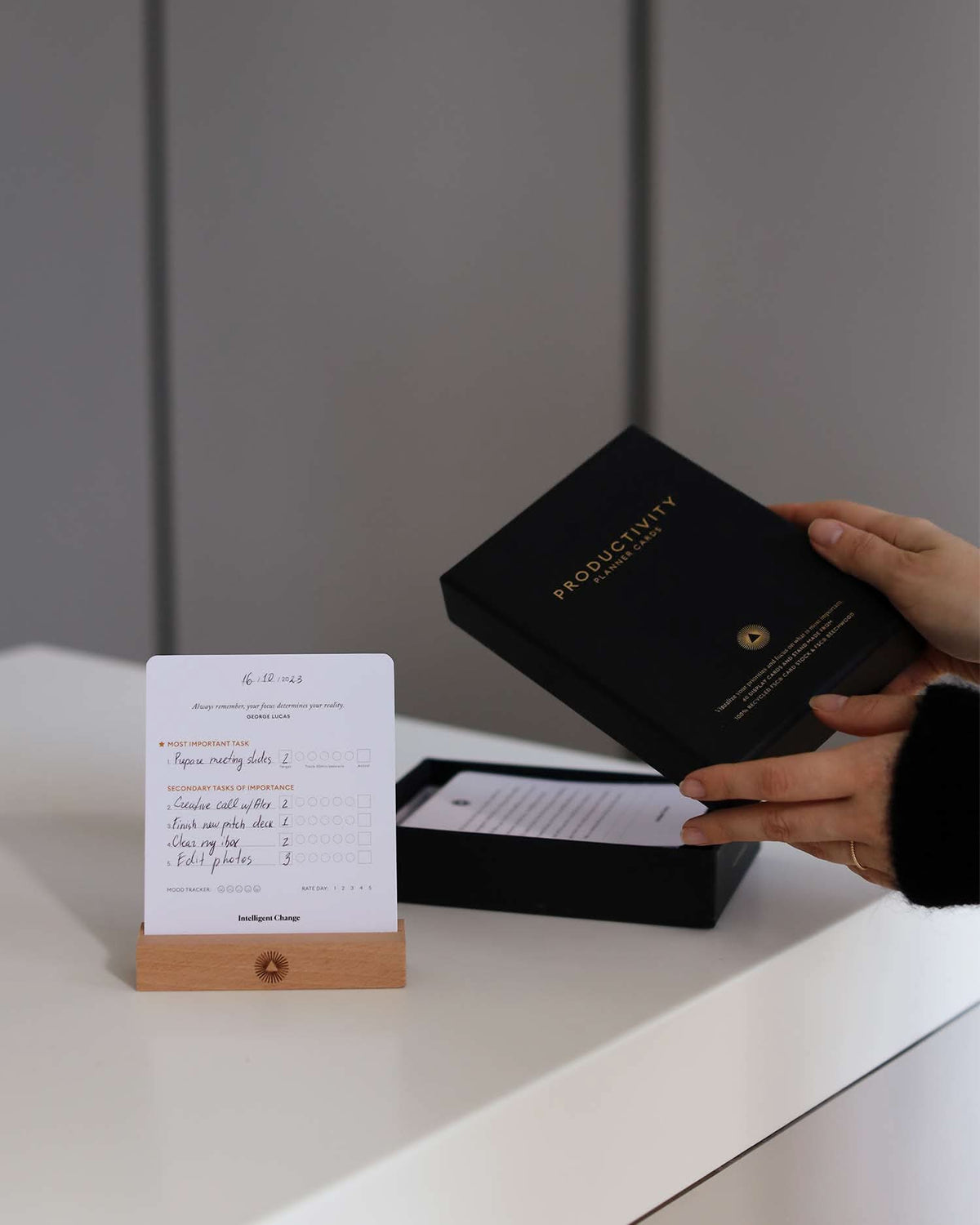 Person opening a black box with a card on a white surface