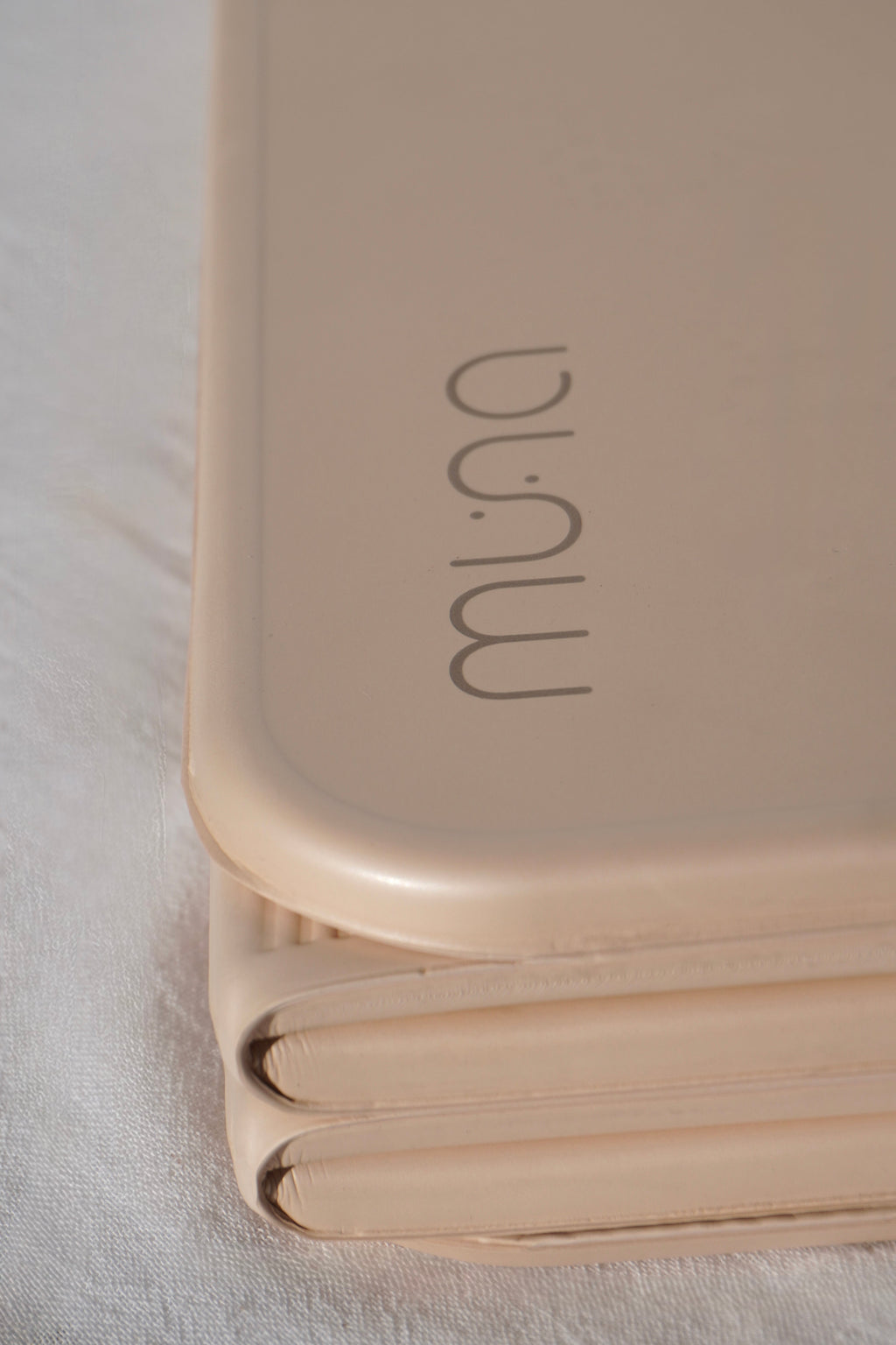 Foldable beige mat with 'muna' branding on a light background