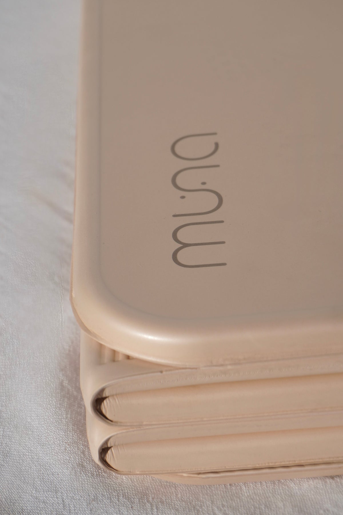 Foldable beige mat with 'muna' branding on a light background