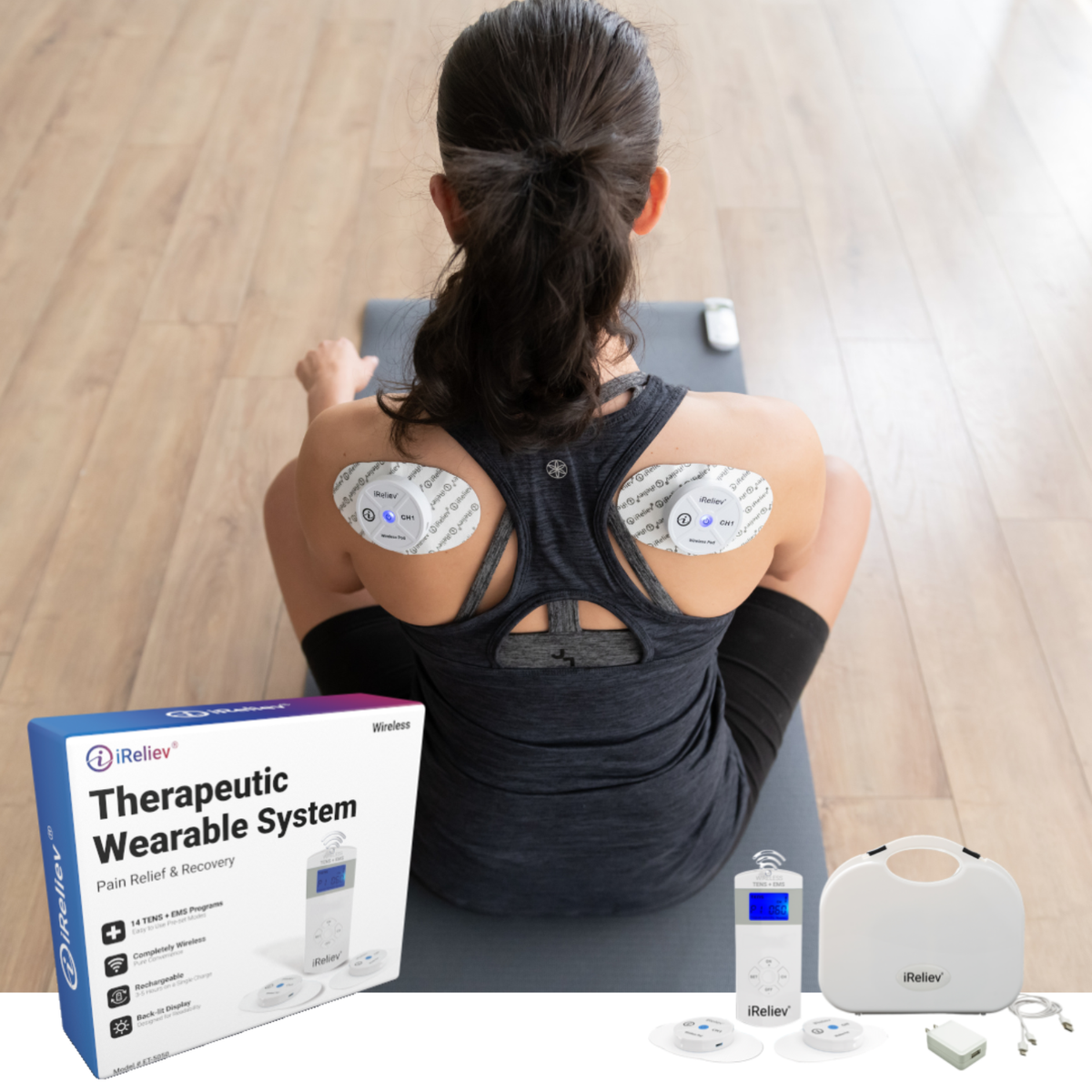 A woman sits on a yoga mat facing away from the camera, showing two back muscles with adhesive electrode pads applied. In the foreground, the product packaging box, a white handheld controller, two electrode pads, and a white carrying case are displayed on a light wood floor background.