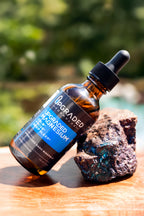 Bottle of Upgraded Magnesium oil with a dropper on a wooden surface with a blurred natural background
