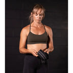 Woman in athletic wear holding a resistance band against a dark background