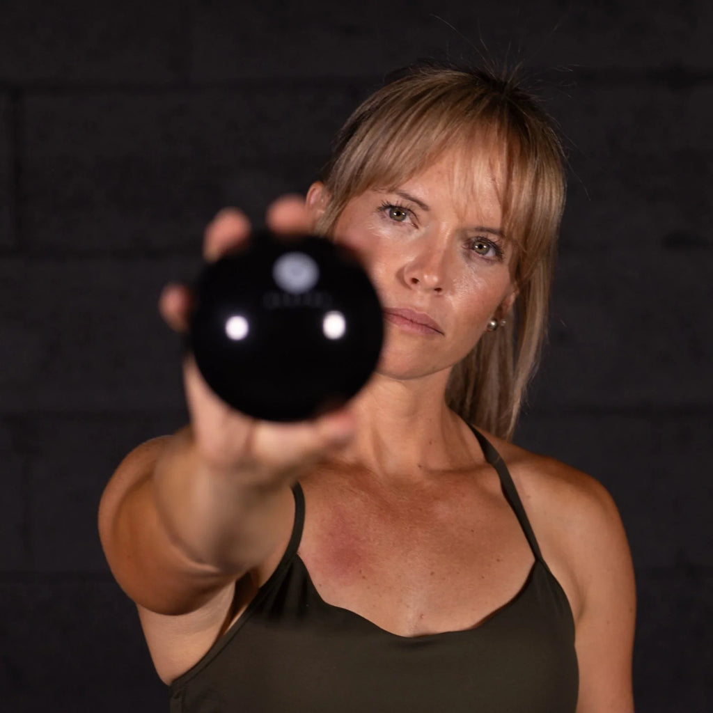 Woman holding a black sphere against a dark background