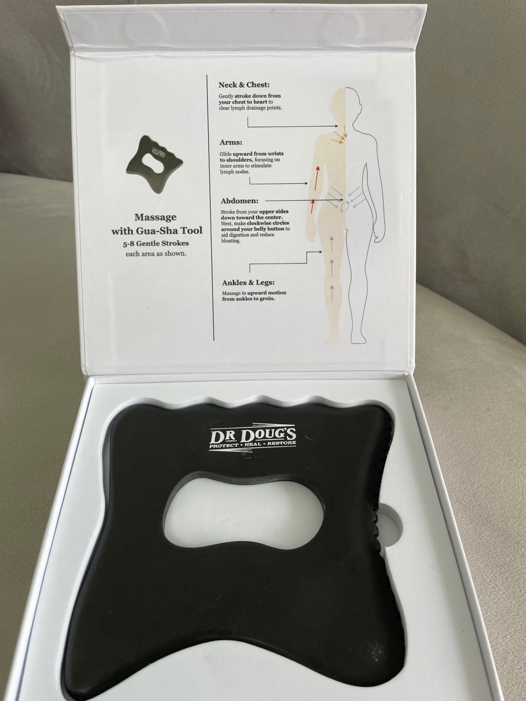 Black massage tool with instructions in a white box on a gray surface