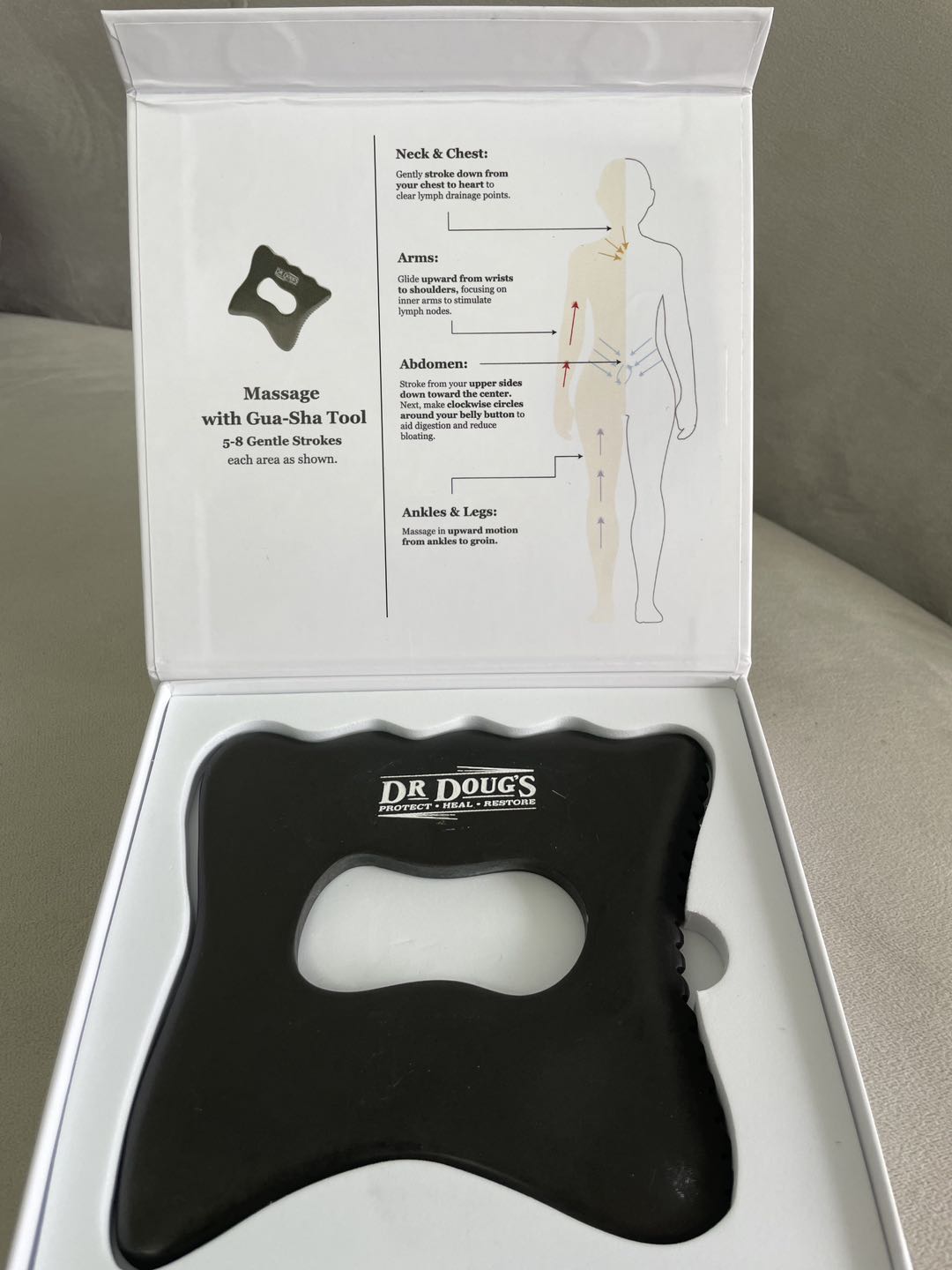 Black massage tool with instructions in a white box on a gray surface