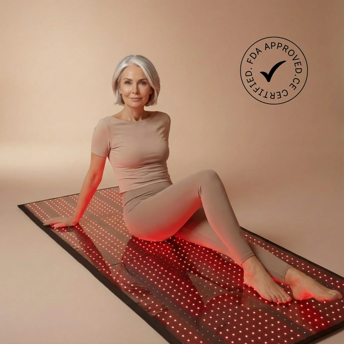 Woman sitting on a red light therapy mat with an FDA approval logo.