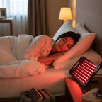 Woman sleeping in bed with a red light device on a nightstand.